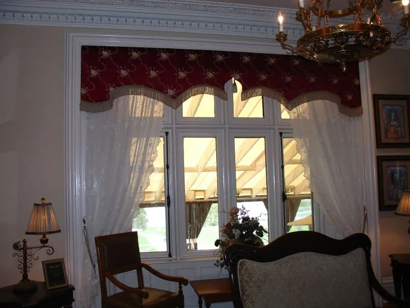 Burgundy scalloped valance with white sheer curtains on a paned window
