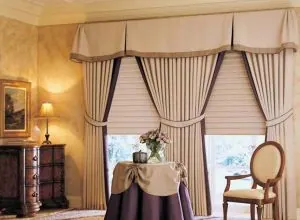 Beige pleated valance with tied-back drapes and shade in a classic room