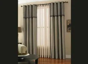 Grey striped curtains with patterned header over cream sheers on a rod