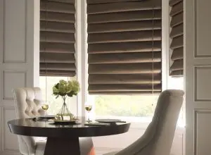 Taupe Roman shades in a dining nook with tufted white chairs