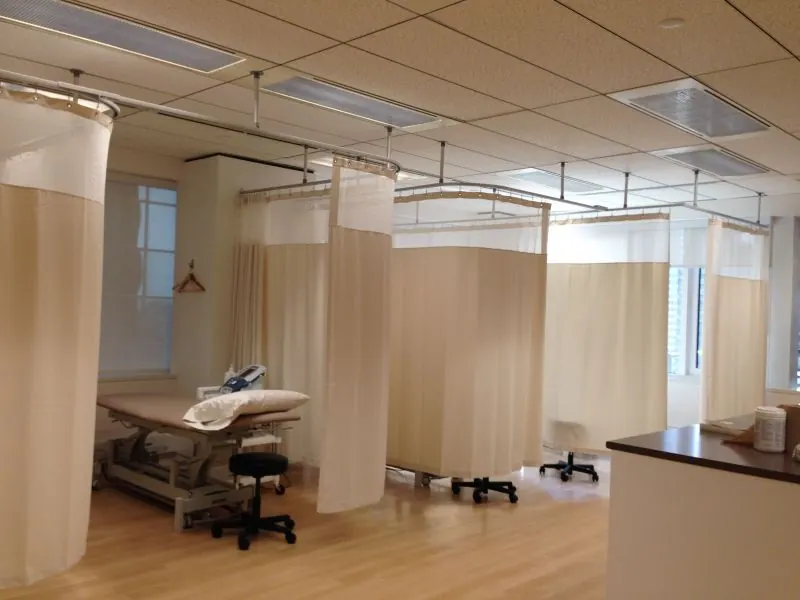 Cream track privacy curtains in a treatment room with exam tables
