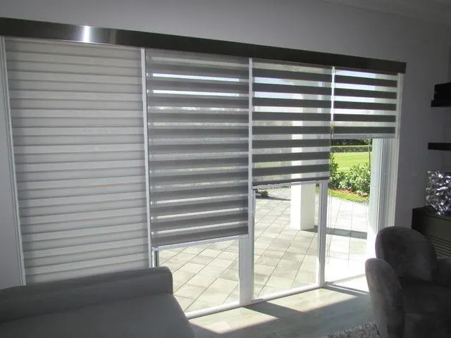 Grey duo shades on a sliding patio door, open to a sunny terrace