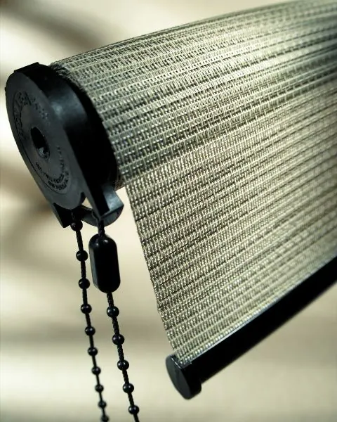 Detail of a grey woven roller shade with black chain and bracket