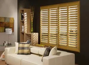 Golden wood shutters behind a cream sofa in a contemporary living room