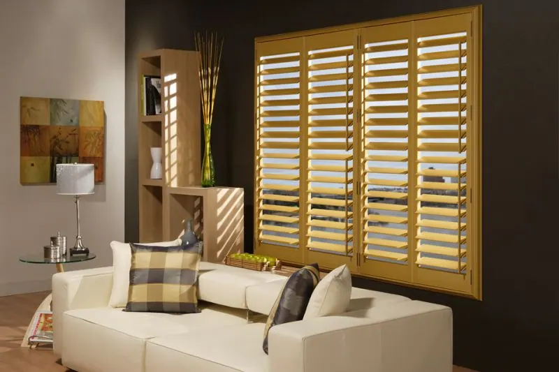 Honey-toned wood shutters above a white sofa with checked cushions