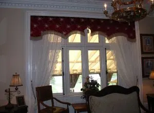 Red patterned valance and white sheers on a small-paned window