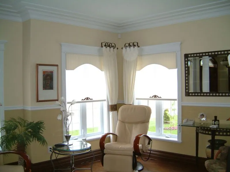 Corner window with cream scalloped shades and a decorative rod