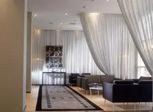 Flowing white sheer drapes in a large lounge with black leather sofas