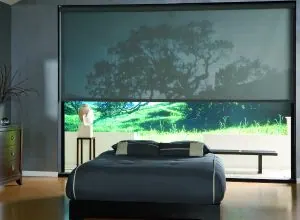 Large solar roller shade over a landscape view in a bedroom