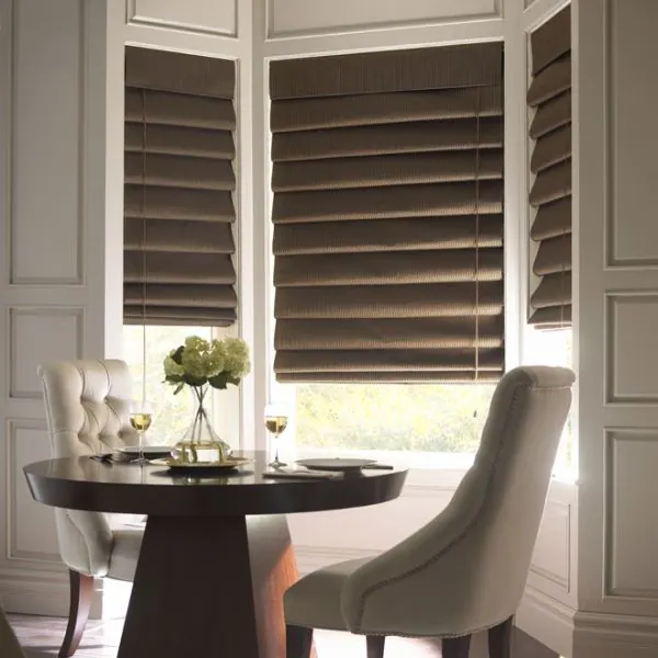 Dark brown Roman shades in a bay window above a small dining table
