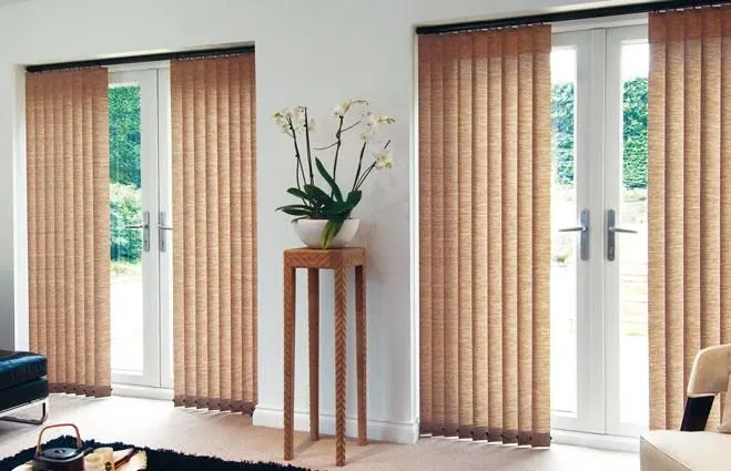 Orange-toned vertical blinds on French doors with an orchid on a stand