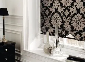 Black and cream damask Roman shade on a window with silver vases
