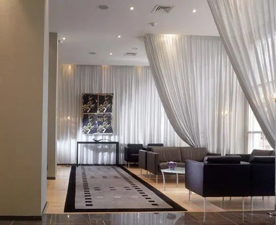Billowing white sheer drapes in a lounge with black leather seating
