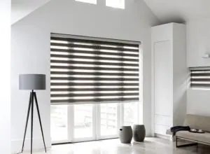 Dark grey zebra shade in a white room with a tripod floor lamp