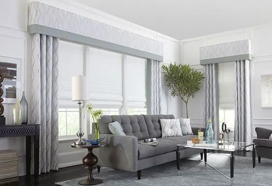 White Roman shades with grey box valances and drapes in a tidy lounge