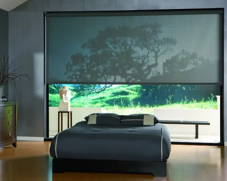 Lowered solar roller shade over a nature view in a modern bedroom
