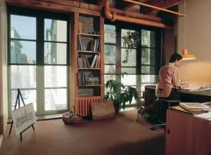 Loft-style study with paned windows and a man working at a desk