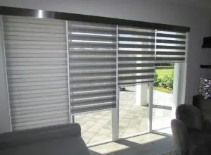 Grey duo shades on a sliding door leading to a sunny patio
