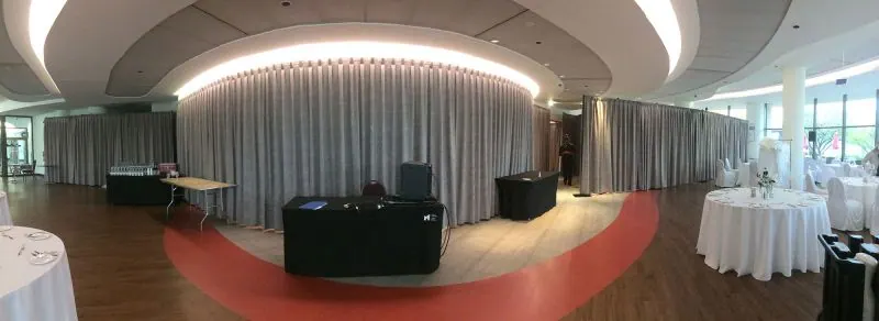 Panoramic view of an event hall with grey curtains and curved ceiling light