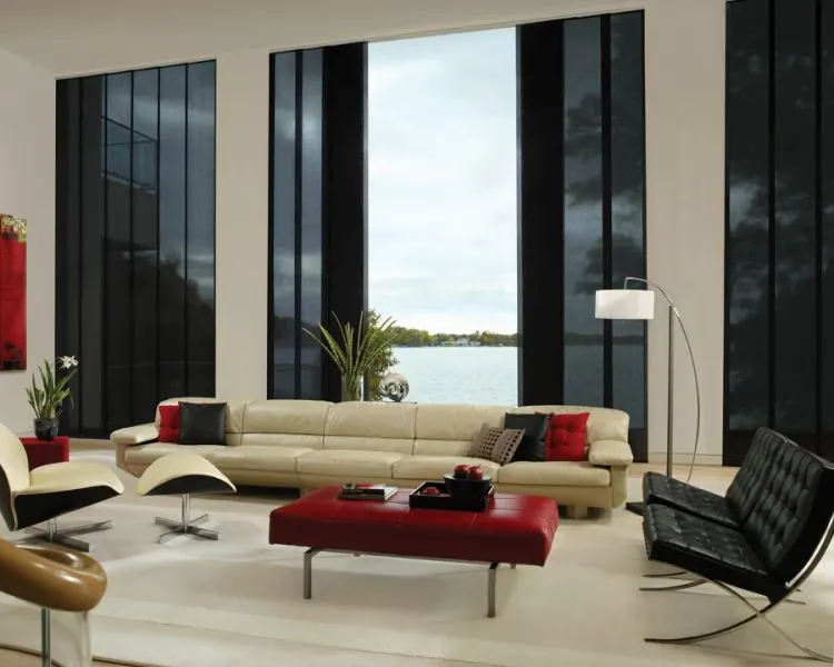 Cream lounge with black panels on tall windows and a red ottoman