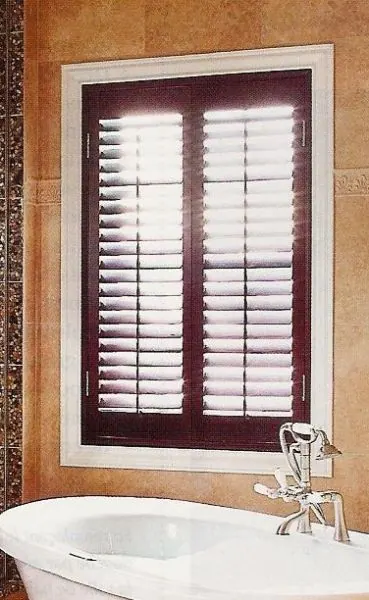 Burgundy shutters with white louvres above a bathtub and tiled wall