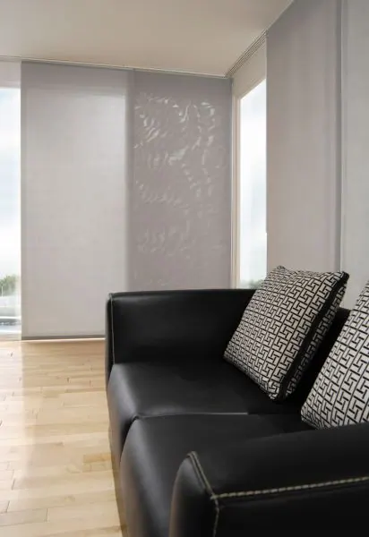 Grey patterned sliding panel beside a black leather sofa and cushions