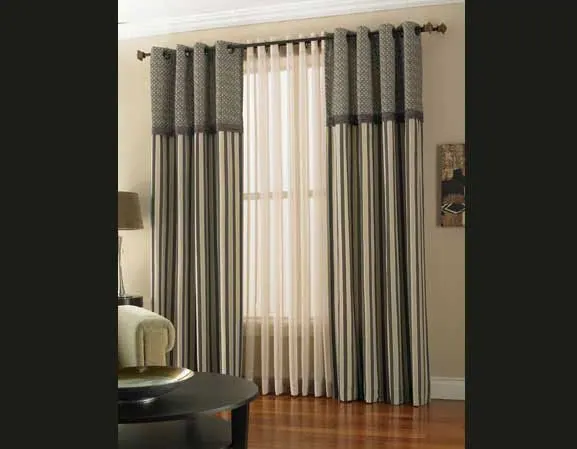 Grey grommet curtains with cream sheers and a patterned header in a lounge